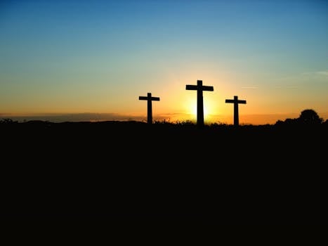 About Us Silhouette of three crosses against a vibrant sunset sky.